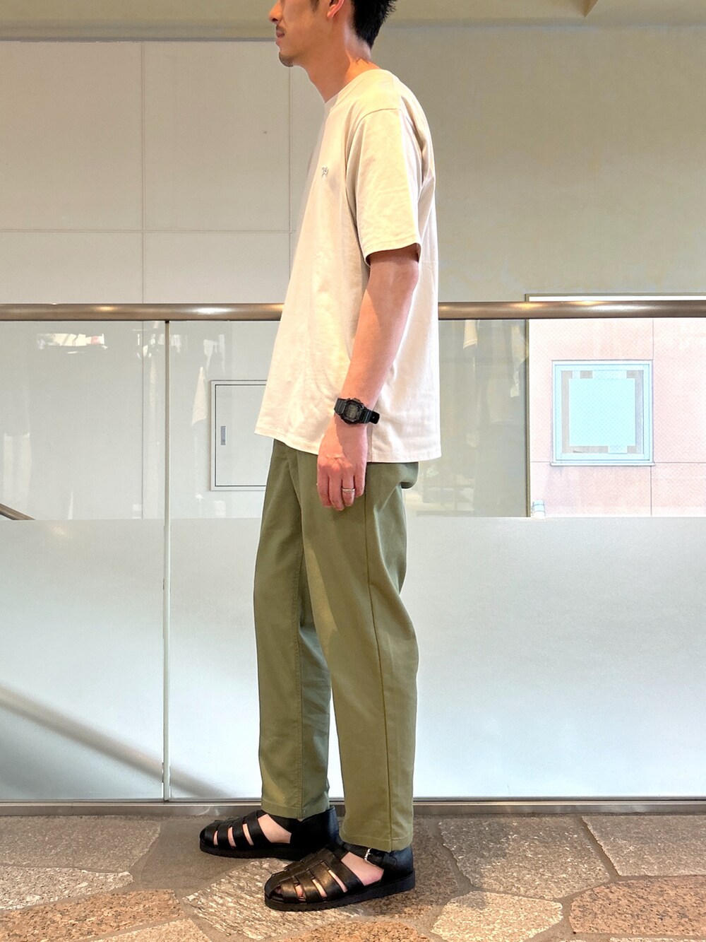 ベージュ系のTシャツ/カットソー、グリーン系のデニムパンツ、ブラック系のサンダルを着用したメンズの夏コーディネートの3枚目の写真