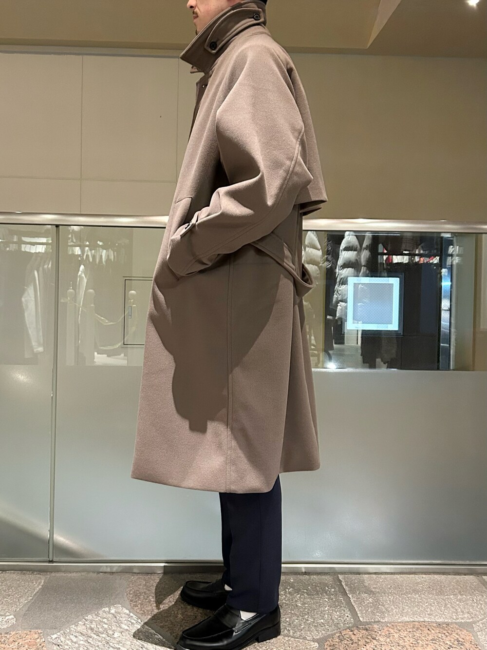 ブラウン系のステンカラーコート、ブルー系のテーラードジャケット、ブルー系のスラックスを着用したメンズの冬コーディネートの3枚目の写真