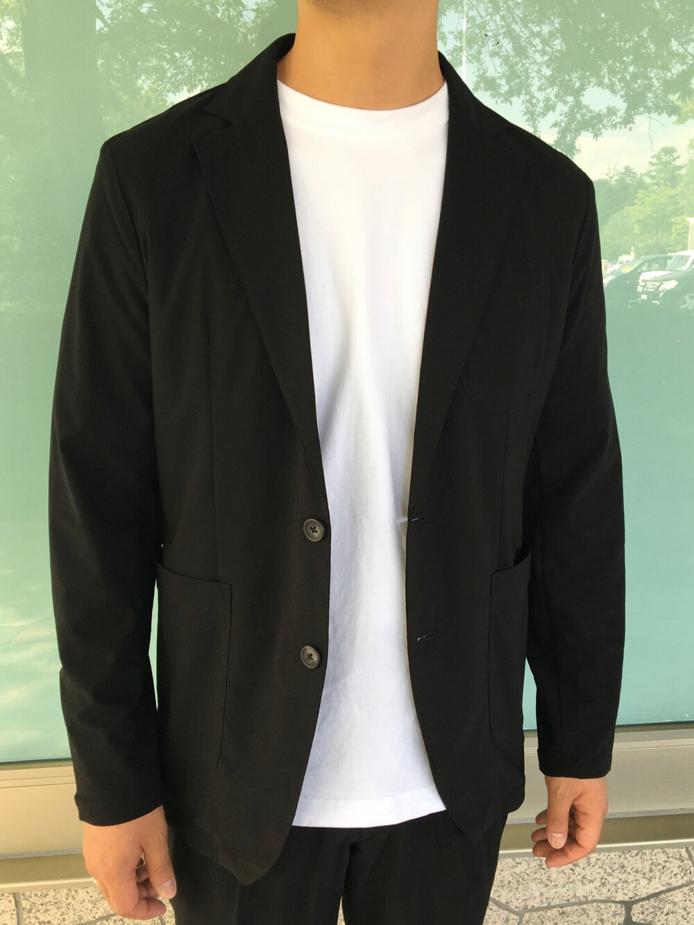 ブラック系のテーラードジャケット、ブラック系のスラックス、ホワイト系のTシャツ/カットソーを着用したメンズの夏コーディネートの4枚目の写真