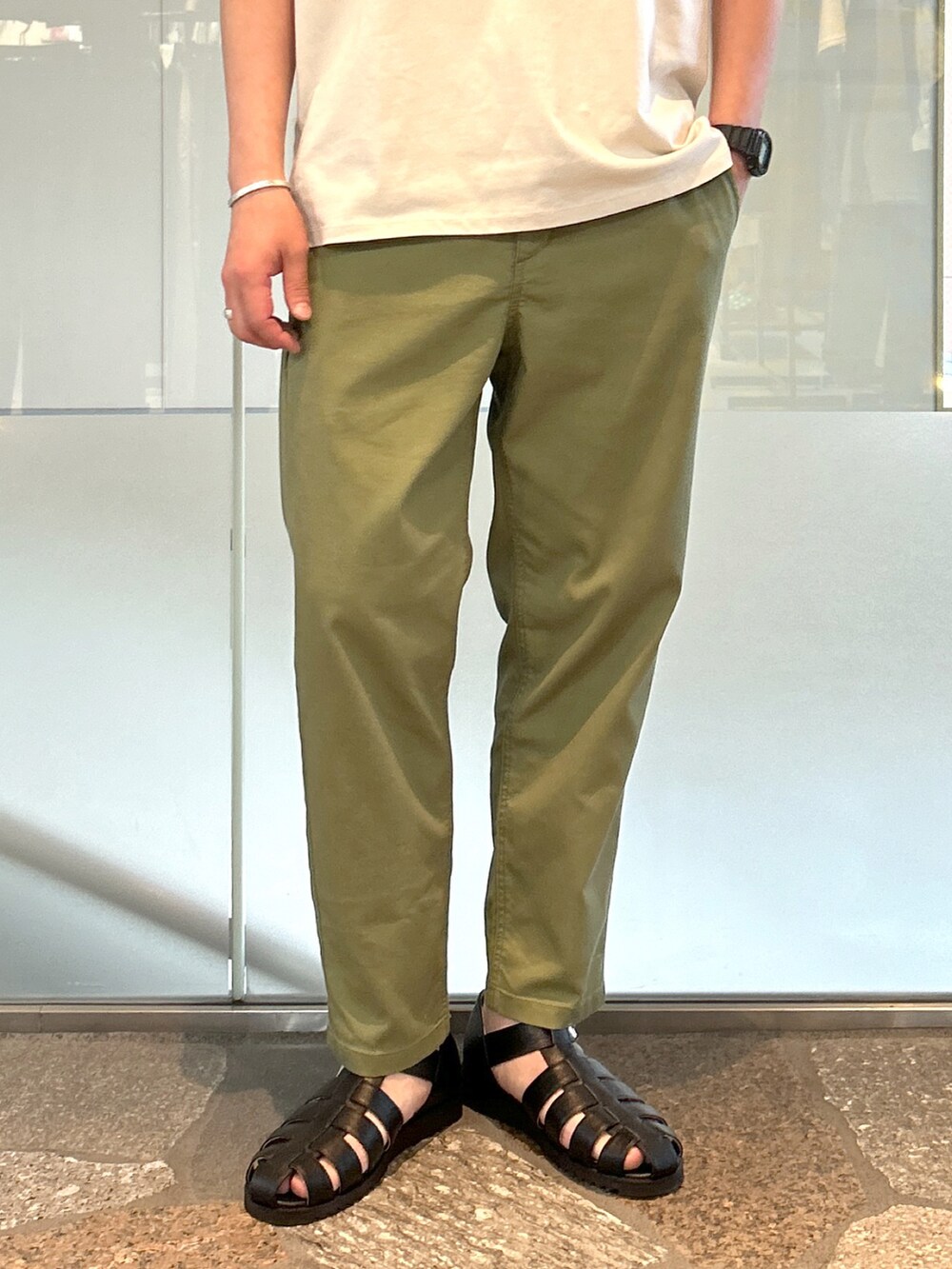 ベージュ系のTシャツ/カットソー、グリーン系のデニムパンツ、ブラック系のサンダルを着用したメンズの夏コーディネートの2枚目の写真