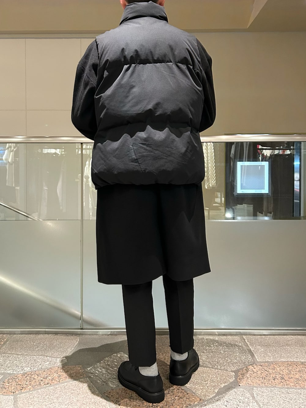 ブラック系のダウンベスト、ブラック系のチェスターコート、ブラック系のテーラードジャケットを着用したメンズの冬コーディネートの3枚目の写真