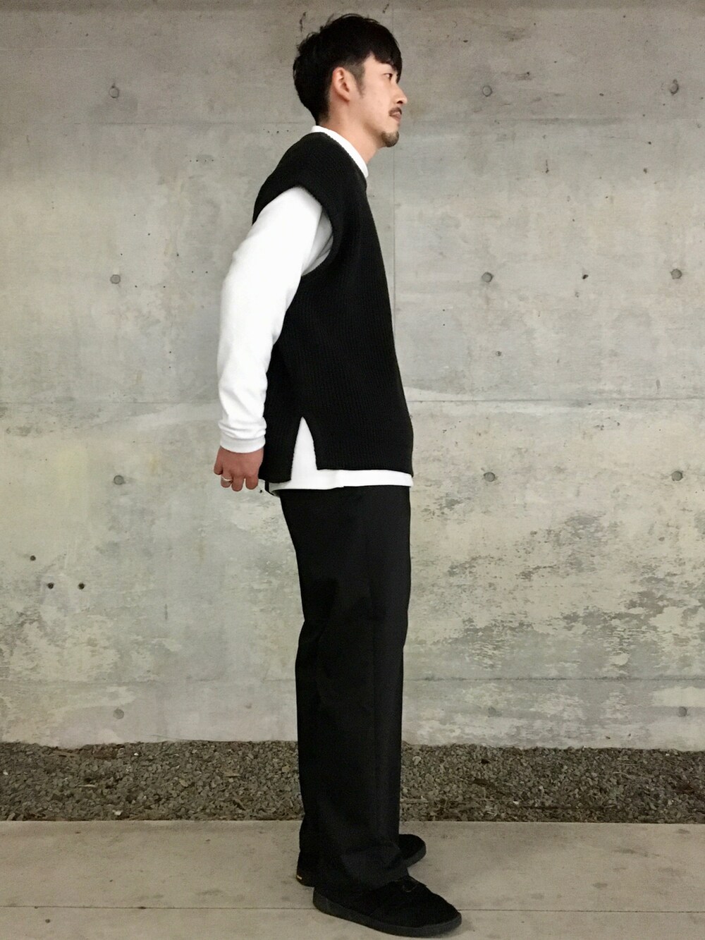 ブラック系のベスト、ホワイト系のTシャツ/カットソー、ブラック系のスラックスを着用したメンズの冬コーディネートの5枚目の写真