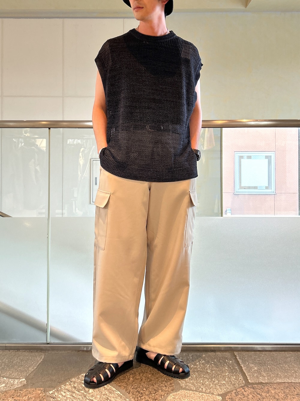 グレー系のベスト、ブラック系のタンクトップ、ベージュ系のカーゴパンツを着用したメンズの春コーディネートの2枚目の写真