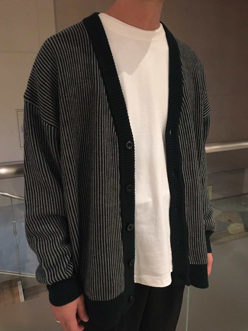 グリーン系のカーディガン/ボレロ、ホワイト系のTシャツ/カットソー、ブラック系のスラックスを着用したメンズの秋コーディネートの2枚目の写真