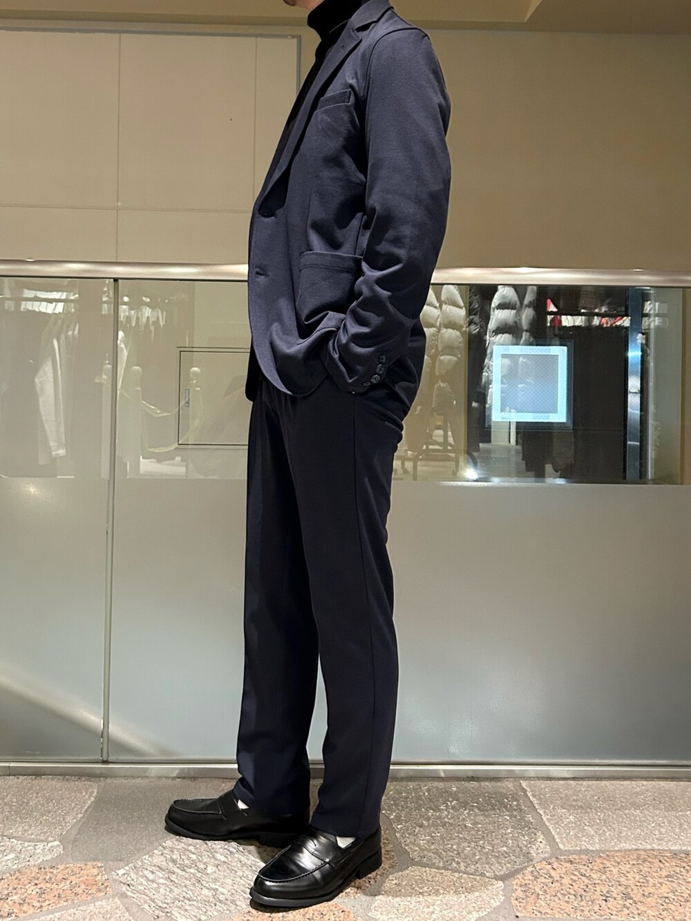 ブルー系のテーラードジャケット、ブルー系のスラックス、ブラック系のニット/セーターを着用したメンズの冬コーディネートの2枚目の写真