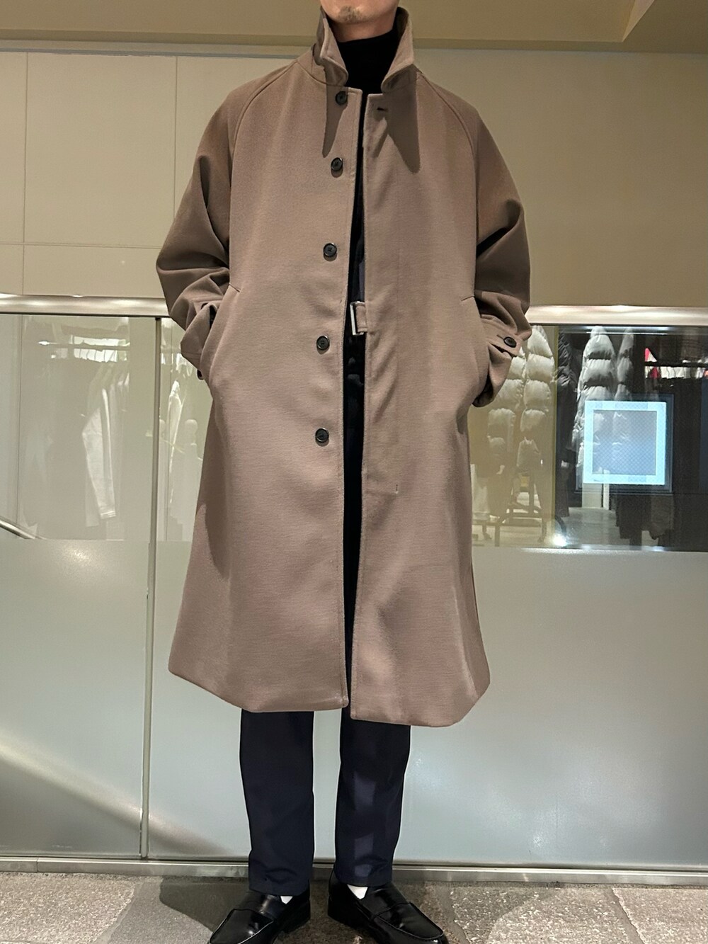 ブラウン系のステンカラーコート、ブルー系のテーラードジャケット、ブルー系のスラックスを着用したメンズの冬コーディネートの2枚目の写真