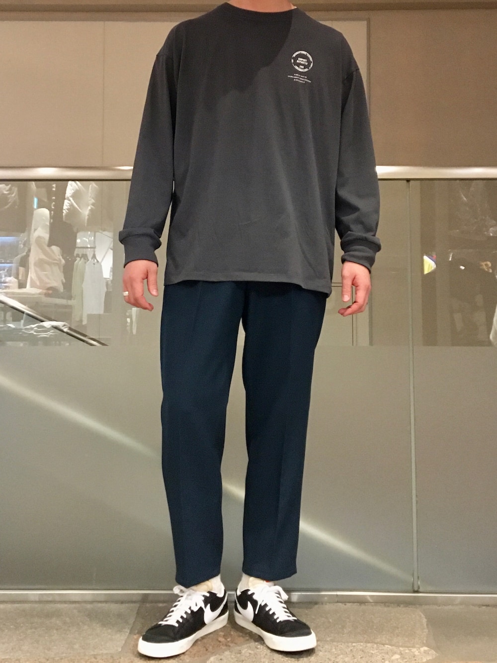 グリーン系のステンカラーコート、グレー系のTシャツ/カットソー、グリーン系のその他パンツを着用したメンズの春コーディネートの5枚目の写真