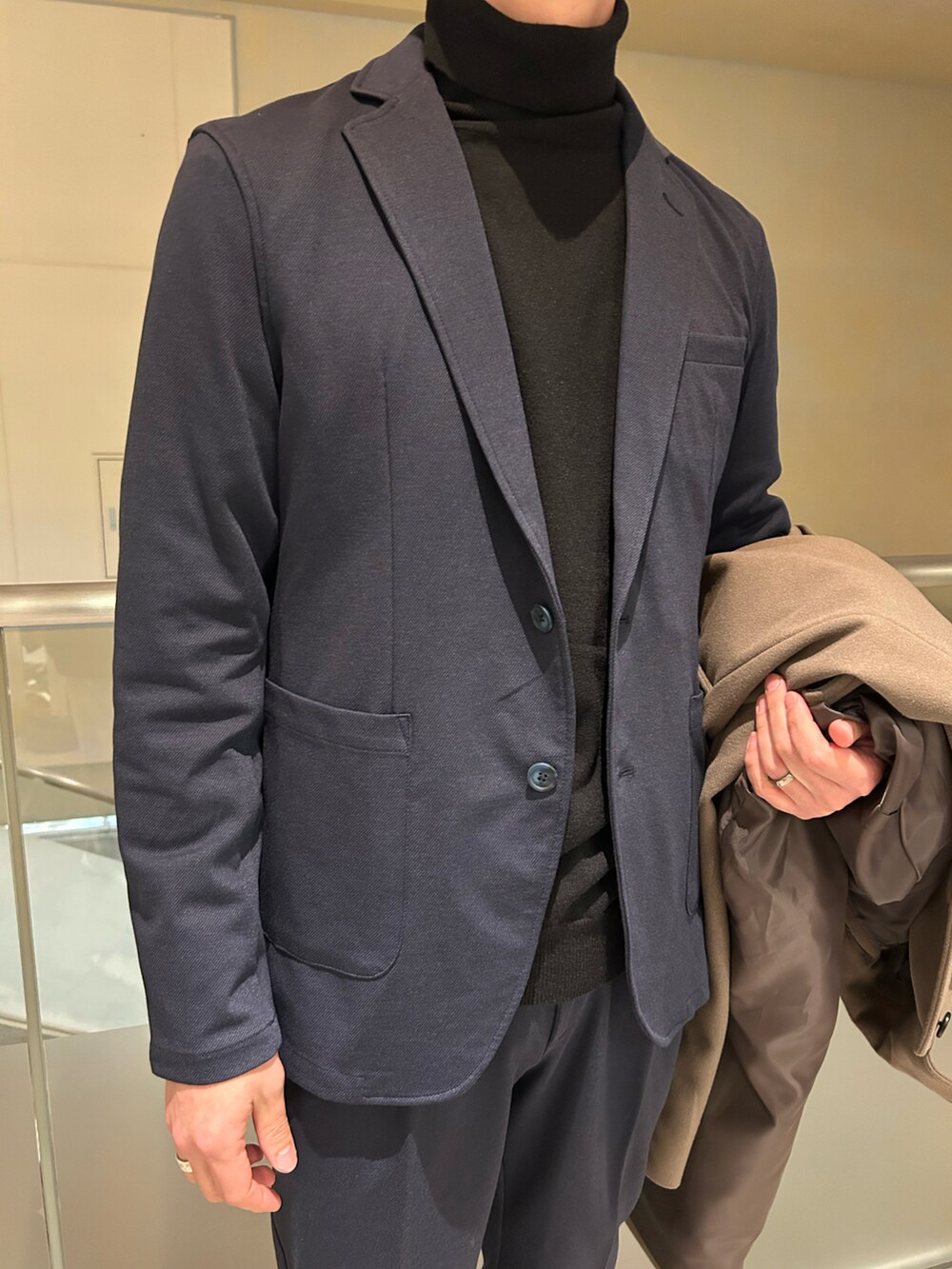 ブルー系のテーラードジャケット、ブルー系のスラックス、ブラック系のニット/セーターを着用したメンズの冬コーディネートの3枚目の写真