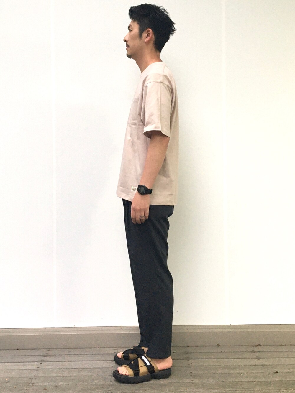 ベージュ系のTシャツ/カットソー、ブラック系のスラックスを着用したメンズの春コーディネートの2枚目の写真