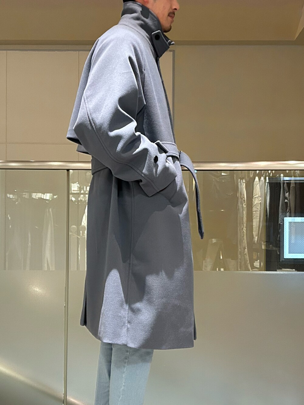 ブルー系のステンカラーコート、パープル系のニット/セーター、グレー系のデニムパンツを着用したメンズの冬コーディネートの3枚目の写真