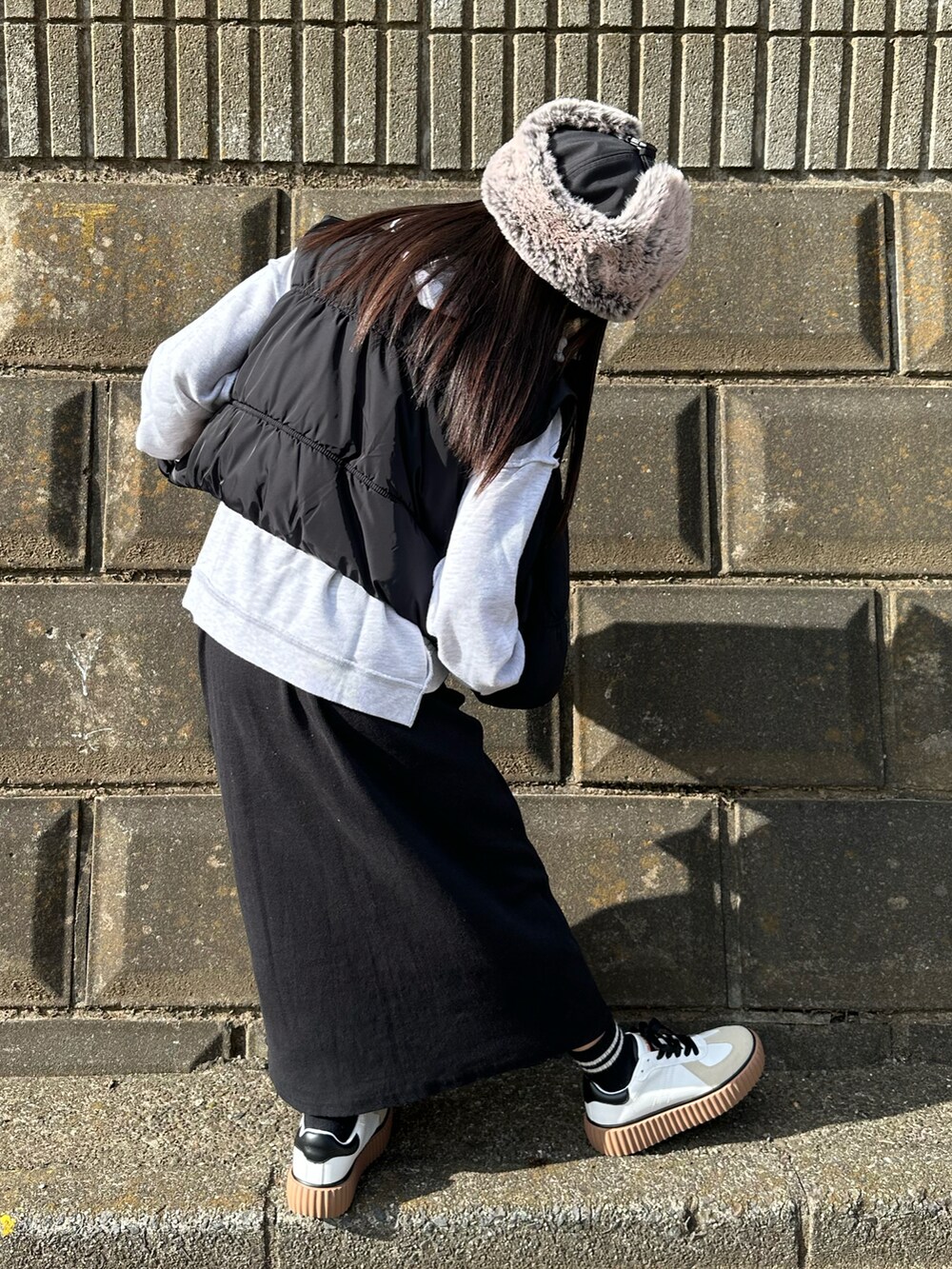 グレー系のパーカー、ブラック系のダウンベスト、ブラック系のスカートを着用したキッズの冬コーディネートの3枚目の写真