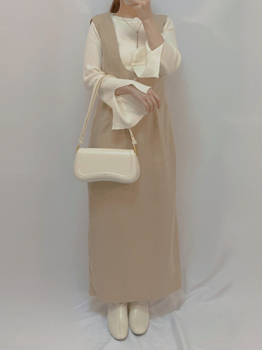 ホワイト系のシューズ、ホワイト系のショルダーバッグ、ホワイト系のニット/セーターを着用したレディースの秋コーディネートの2枚目の写真