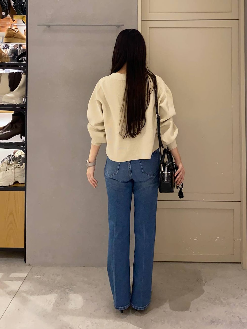 ホワイト系のカーディガン/ボレロ、ブルー系のデニムパンツ、ブラック系のボストンバッグを着用したレディースの秋コーディネートの2枚目の写真