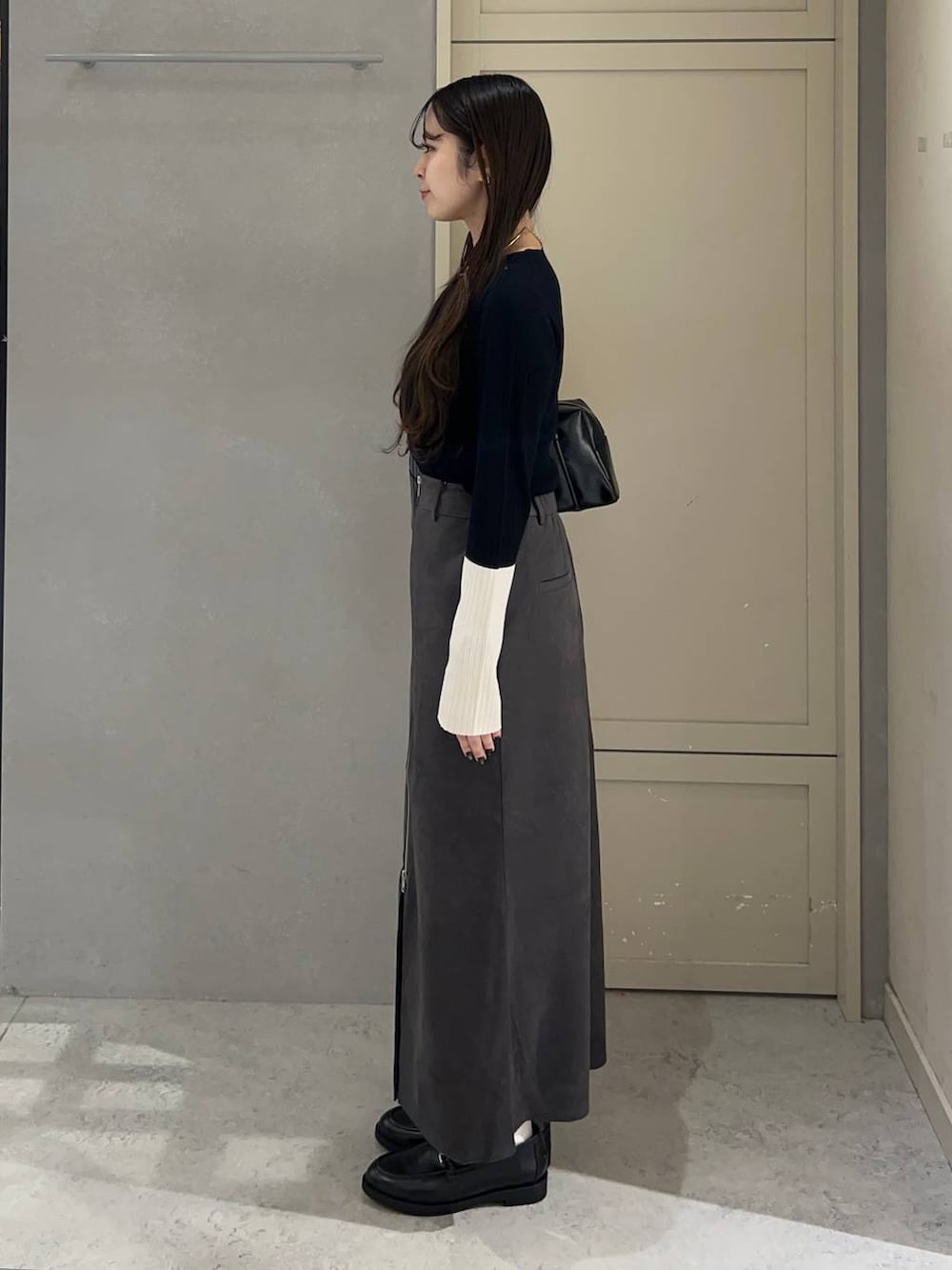 ブラック系のニット/セーター、グレー系のスカート、ブラック系のローファーを着用したレディースの秋コーディネートの3枚目の写真