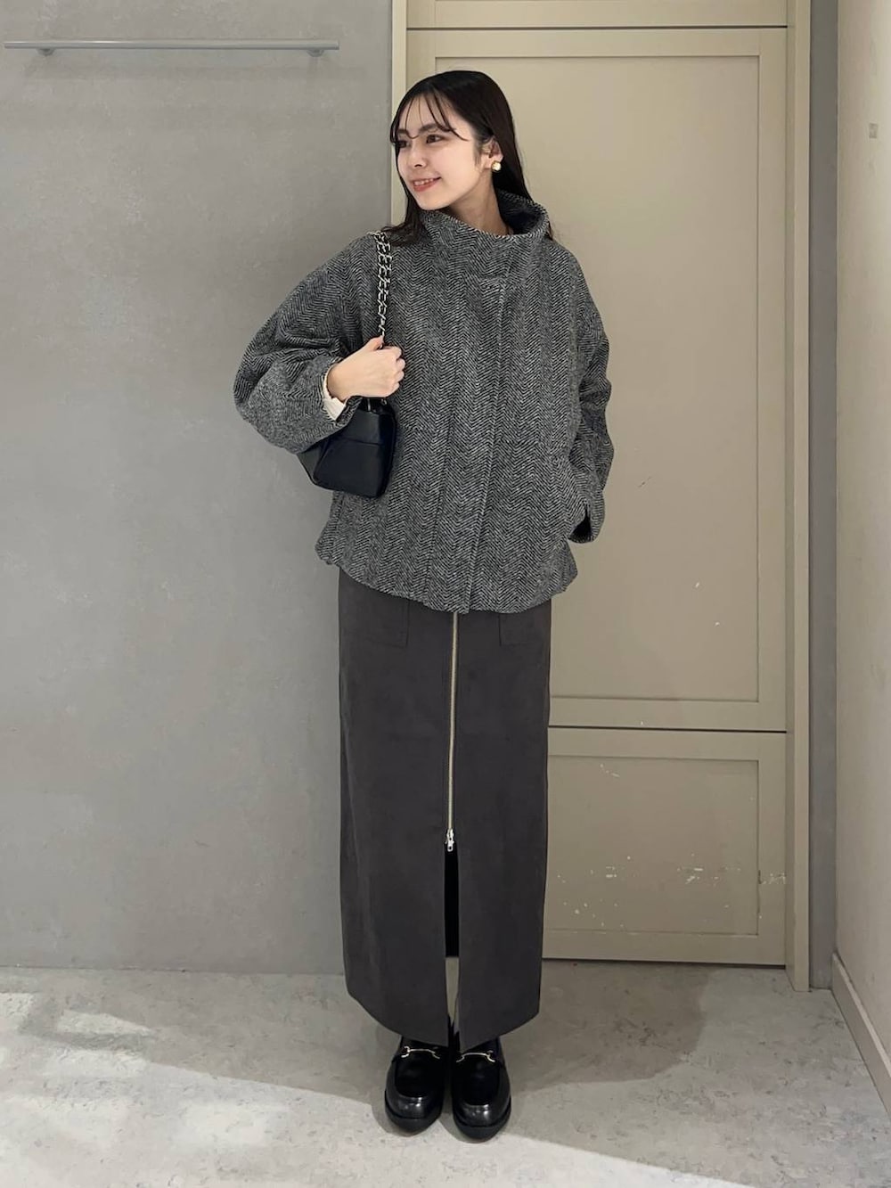 ブラック系のニット/セーター、グレー系のブルゾン、グレー系のスカートを着用したレディースの秋コーディネートの2枚目の写真