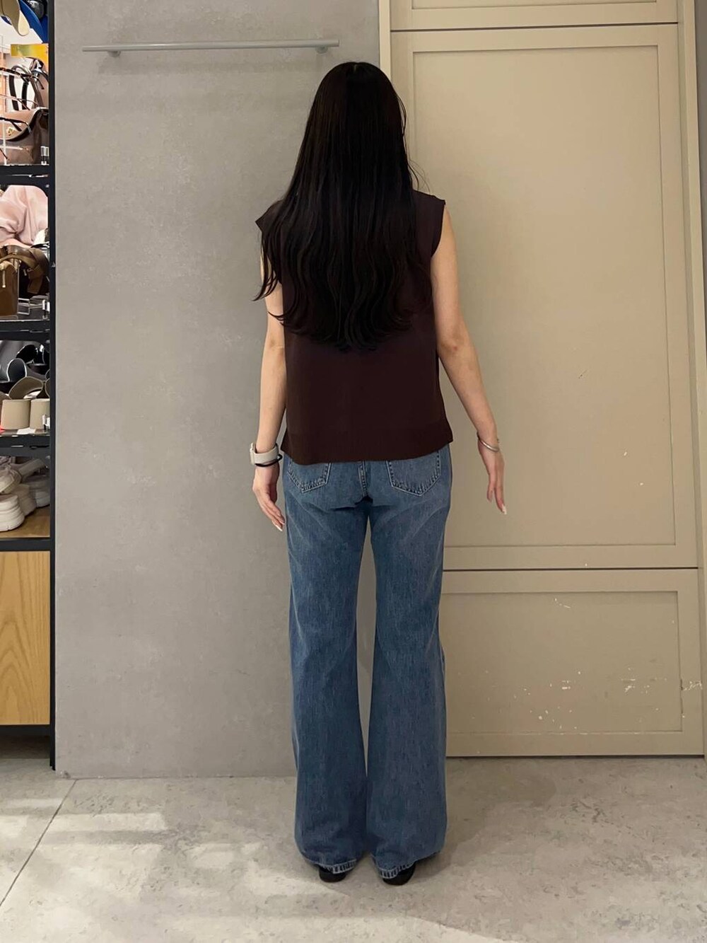 ホワイト系のキャミソール、ブラック系のサンダル、ブルー系のデニムパンツを着用したレディースの夏コーディネートの3枚目の写真