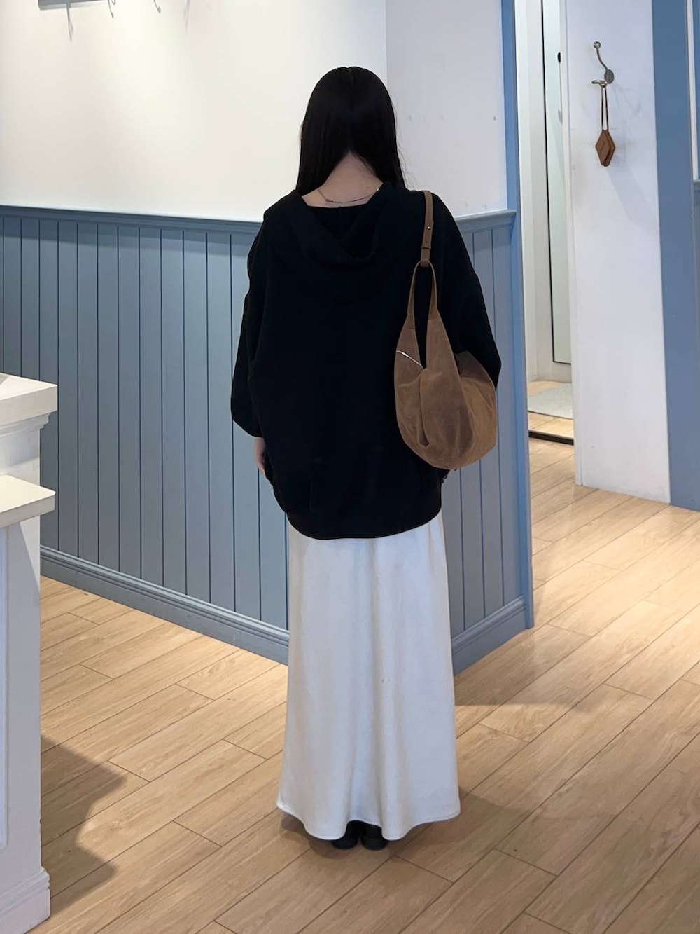 ホワイト系のスカート、ブラック系のパーカー、ブラウン系のショルダーバッグを着用したレディースの春コーディネートの3枚目の写真