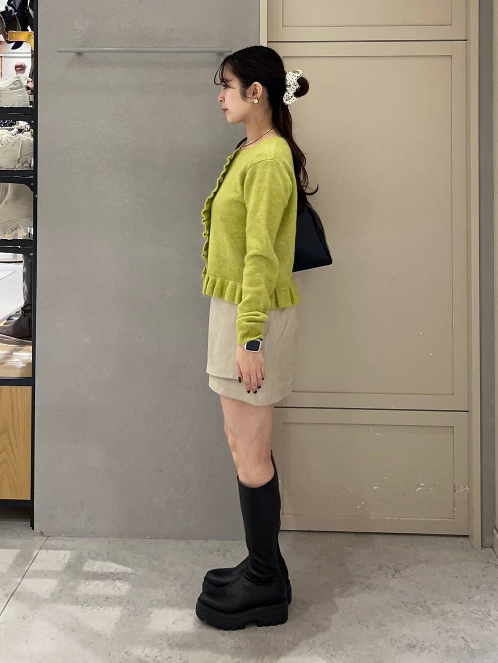 ブラック系のボストンバッグ、ブラック系のブーツ、イエロー系のニット/セーターを着用したレディースの秋コーディネートの2枚目の写真