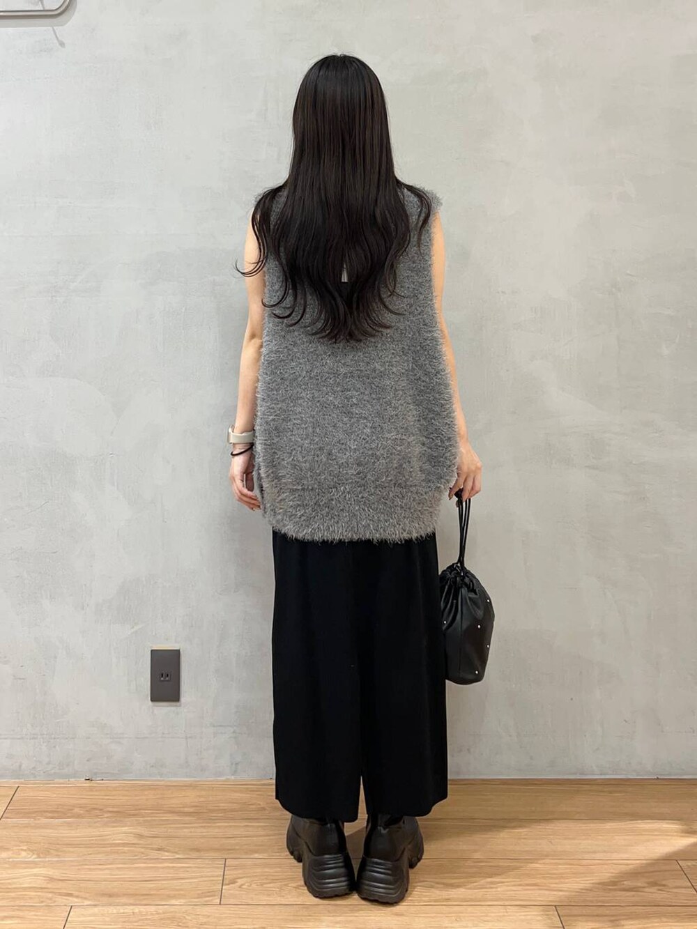 ブラック系のスカート、ブラック系のショルダーバッグ、グレー系のベストを着用したレディースの夏コーディネートの3枚目の写真