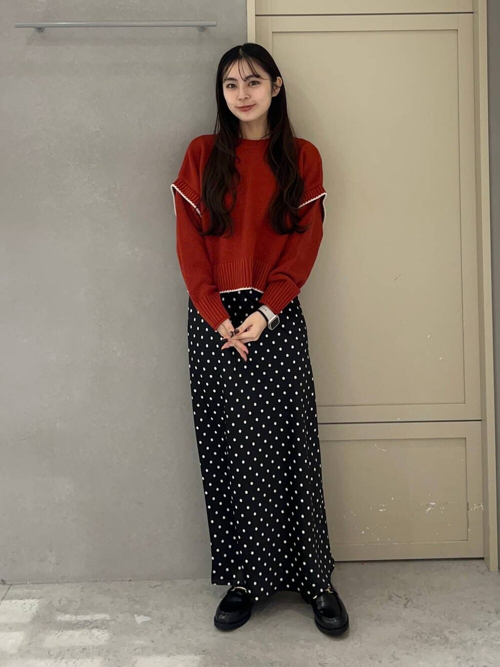ブラック系のスカート、レッド系のニット/セーター、ブラック系のローファーを着用したレディースの秋コーディネートの2枚目の写真