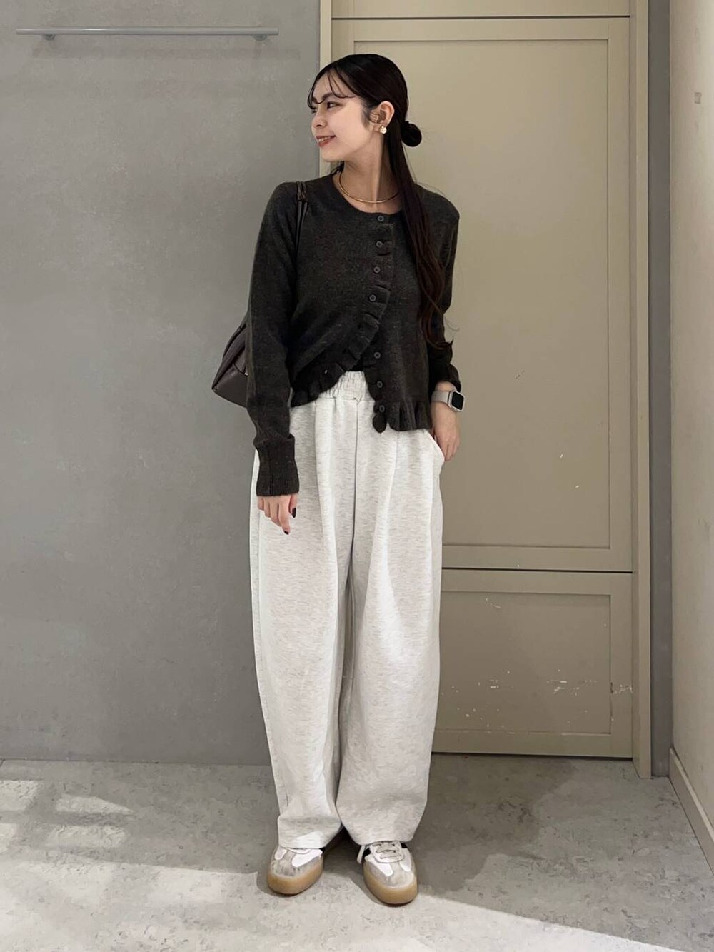 グレー系のスウェットパンツ、ブラウン系のニット/セーター、ブラウン系のボストンバッグを着用したレディースの冬コーディネートの2枚目の写真