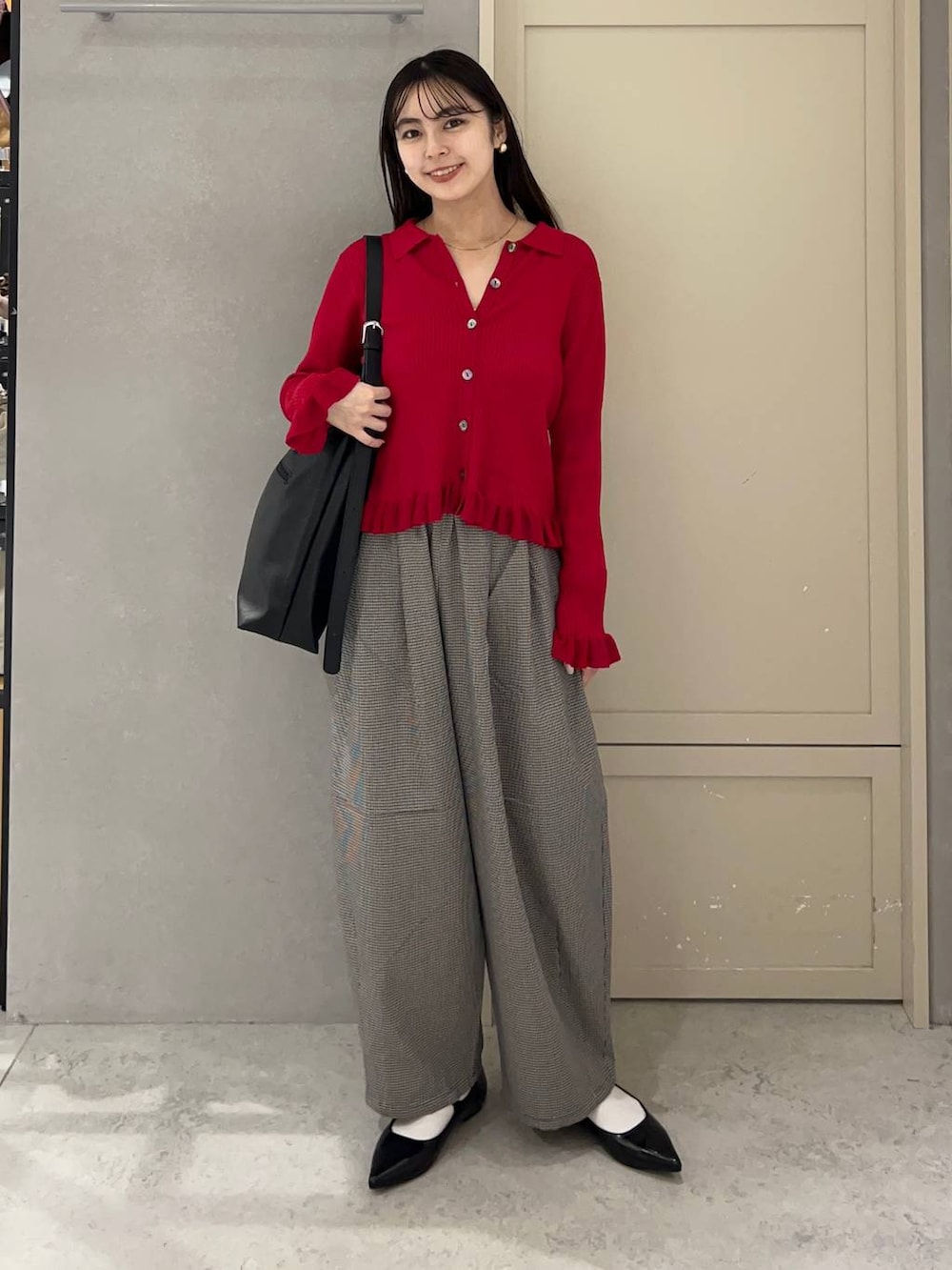 ブラック系のショルダーバッグ、ブラック系のパンプス、レッド系のニット/セーターを着用したレディースの秋コーディネートの2枚目の写真