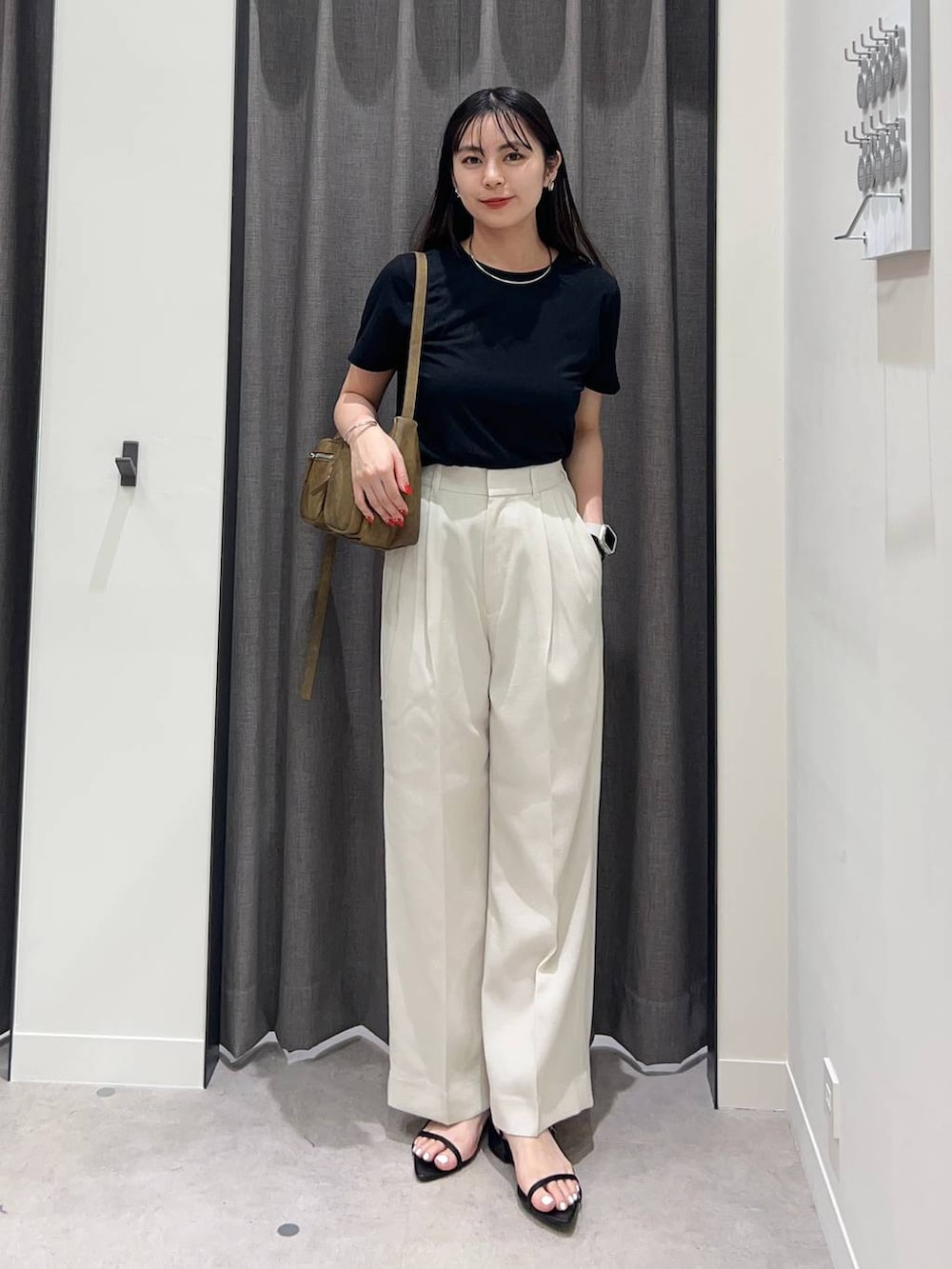ホワイト系のスラックス、ブラック系のサンダル、ブラウン系のショルダーバッグを着用したレディースの夏コーディネートの2枚目の写真