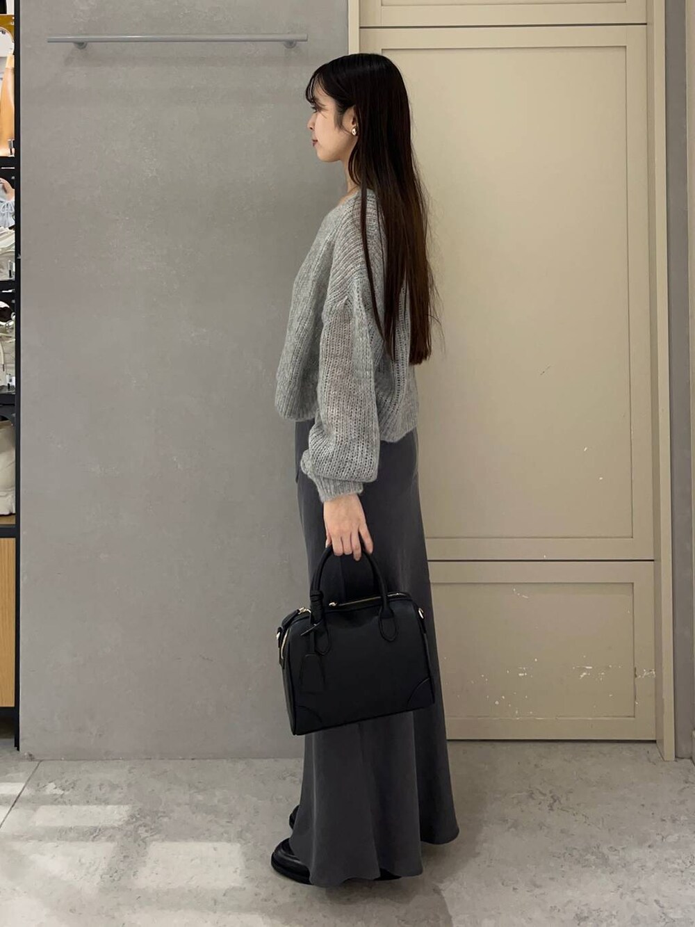ブラック系のショルダーバッグ、グレー系のスカート、ブラック系のローファーを着用したレディースの秋コーディネートの2枚目の写真