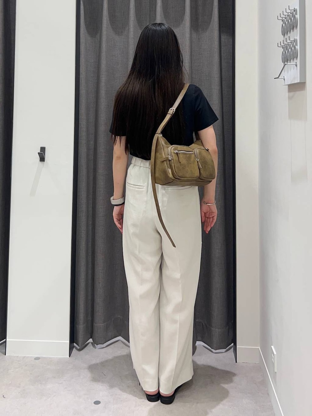 ホワイト系のスラックス、ブラック系のサンダル、ブラウン系のショルダーバッグを着用したレディースの夏コーディネートの4枚目の写真