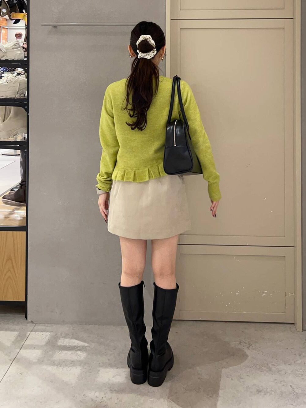 ブラック系のボストンバッグ、ブラック系のブーツ、イエロー系のニット/セーターを着用したレディースの秋コーディネートの3枚目の写真