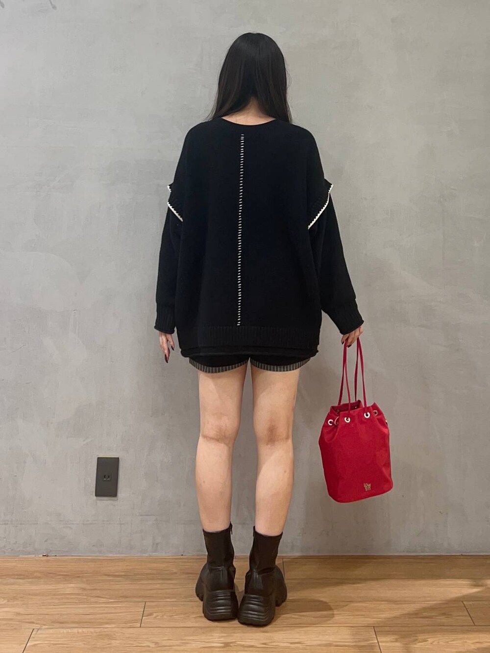 ブラック系のニット/セーター、ブルー系のその他パンツ、ブラック系のブーツを着用したレディースの秋コーディネートの3枚目の写真