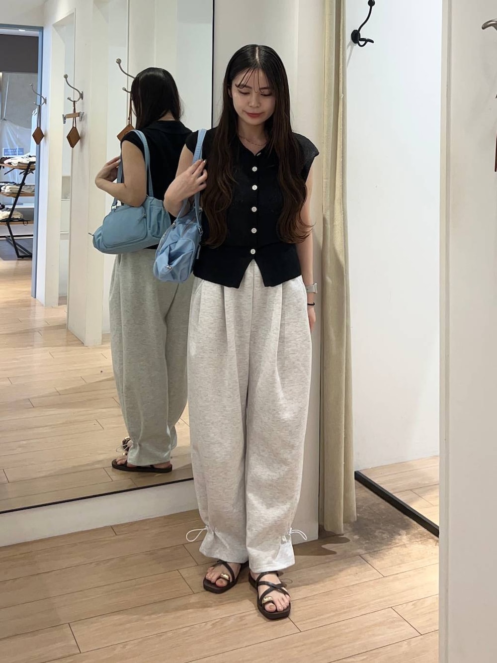 グレー系のスウェットパンツ、ブラック系のベスト、ブラウン系のサンダルを着用したレディースの夏コーディネートの2枚目の写真