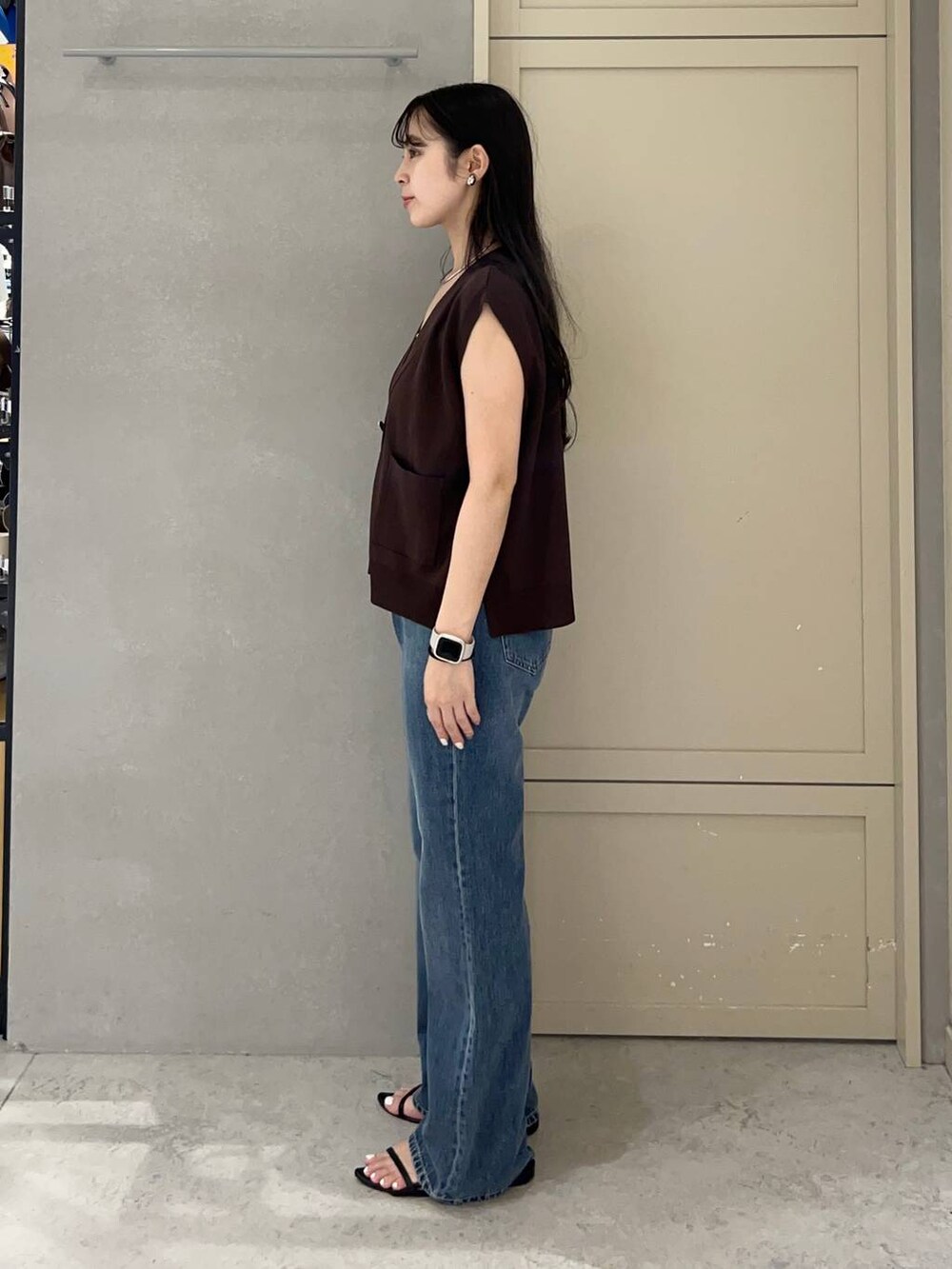 ホワイト系のキャミソール、ブラック系のサンダル、ブルー系のデニムパンツを着用したレディースの夏コーディネートの2枚目の写真