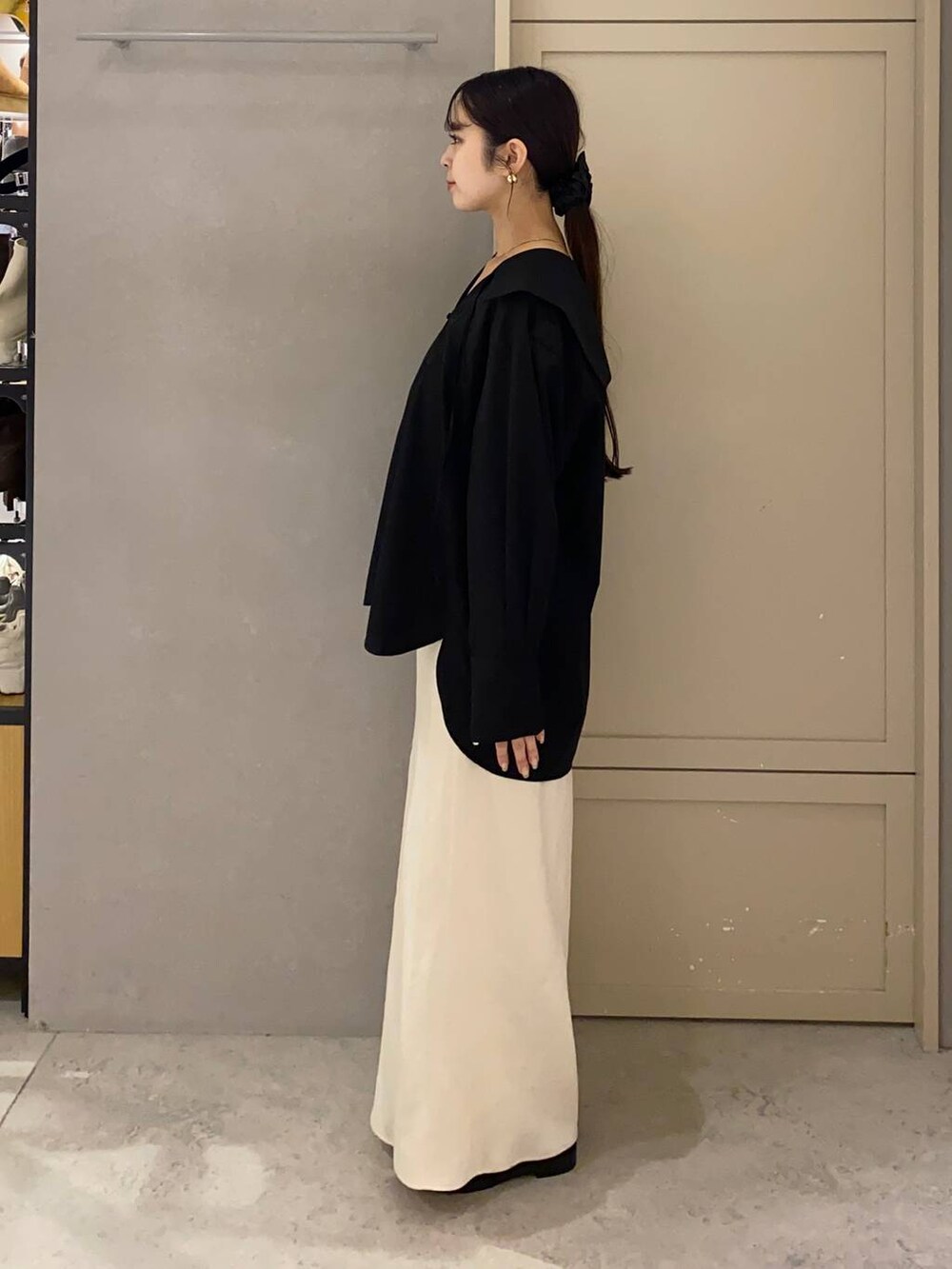 ホワイト系のスカート、ブラウン系のローファー、ブラック系のシャツ/ブラウスを着用したレディースの秋コーディネートの2枚目の写真