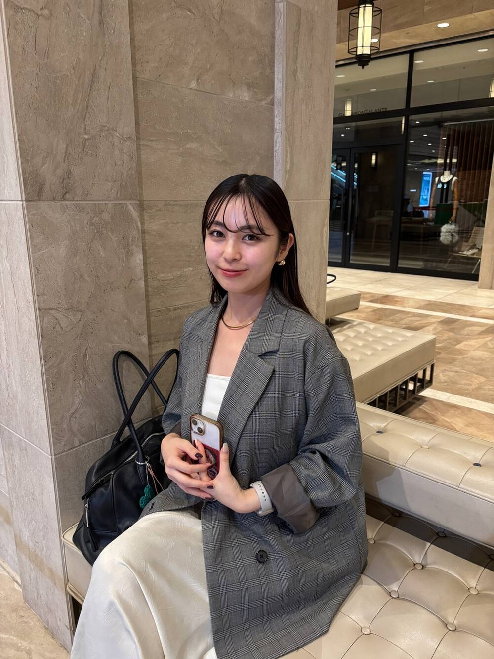 ブラック系のショルダーバッグ、ホワイト系のスカート、グレー系のテーラードジャケットを着用したレディースの秋コーディネートの3枚目の写真