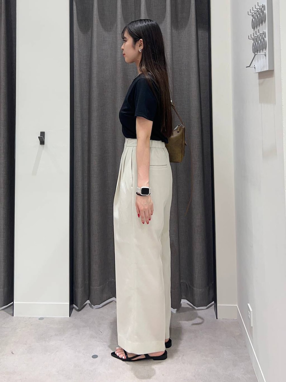 ホワイト系のスラックス、ブラック系のサンダル、ブラウン系のショルダーバッグを着用したレディースの夏コーディネートの3枚目の写真