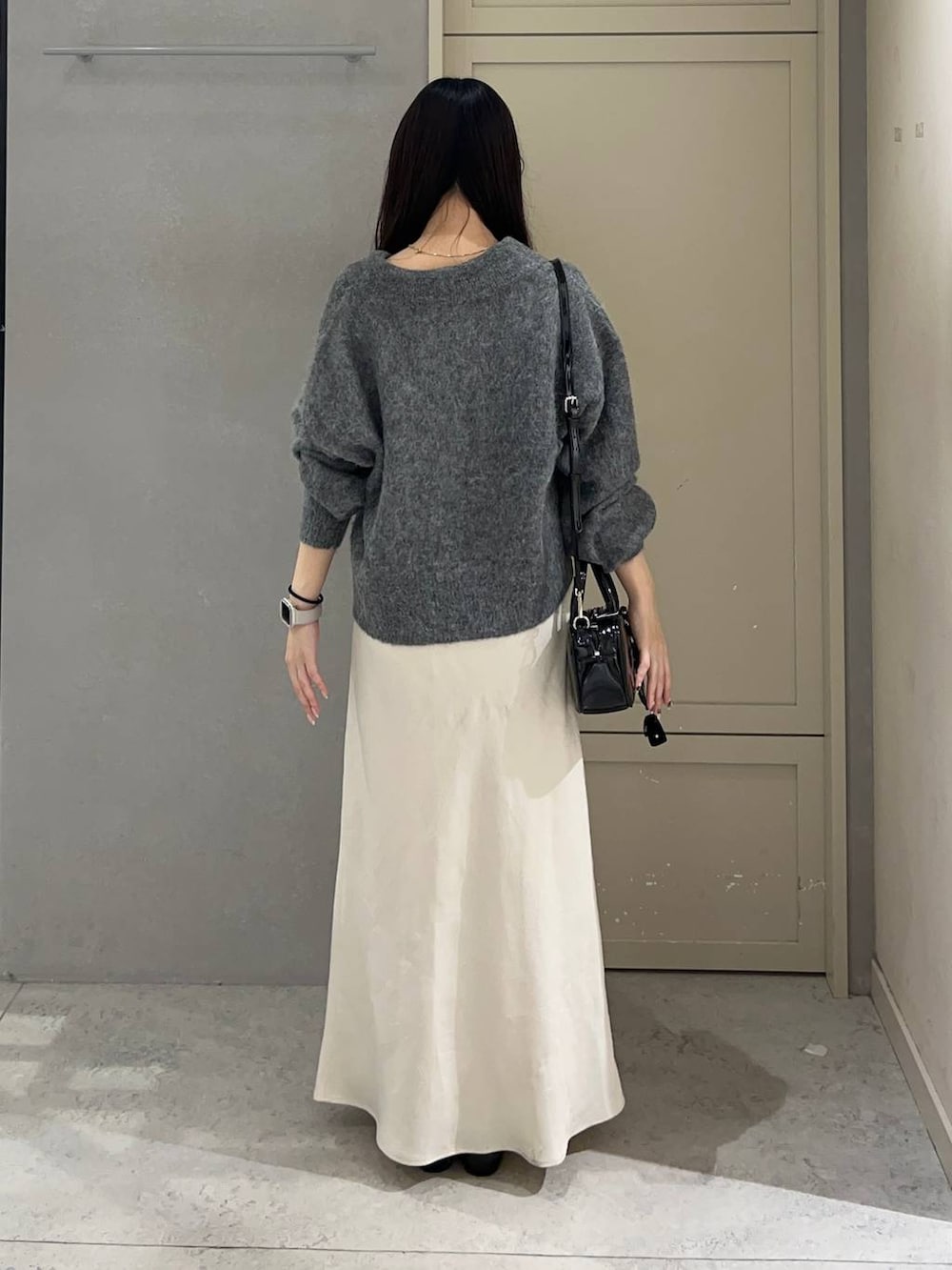 ホワイト系のスカート、ブラック系のパンプス、ブラック系のボストンバッグを着用したレディースの秋コーディネートの3枚目の写真