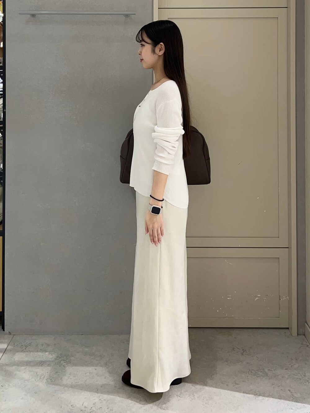 ホワイト系のスカート、ブラウン系のショルダーバッグ、ブラウン系のローファーを着用したレディースの秋コーディネートの2枚目の写真