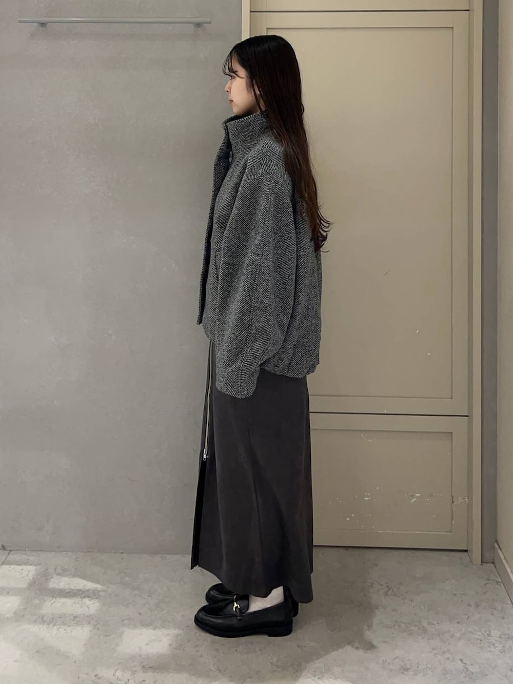 ブラック系のニット/セーター、グレー系のブルゾン、グレー系のスカートを着用したレディースの秋コーディネートの3枚目の写真
