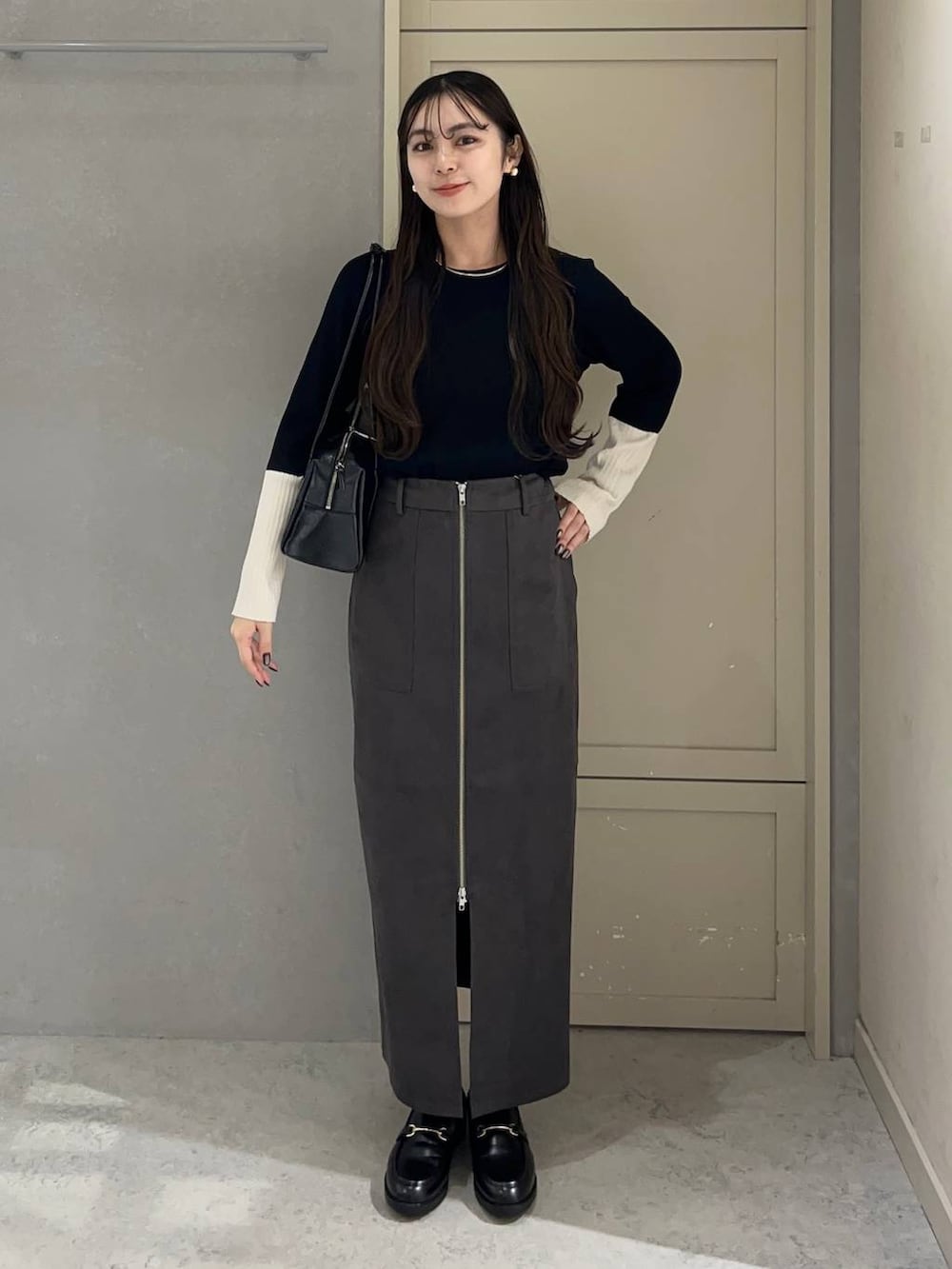 ブラック系のニット/セーター、グレー系のスカート、ブラック系のローファーを着用したレディースの秋コーディネートの2枚目の写真