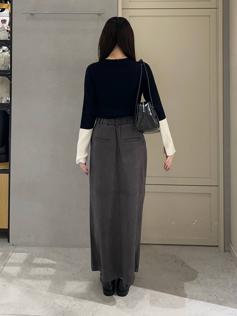 ブラック系のニット/セーター、グレー系のスカート、ブラック系のローファーを着用したレディースの秋コーディネートの4枚目の写真