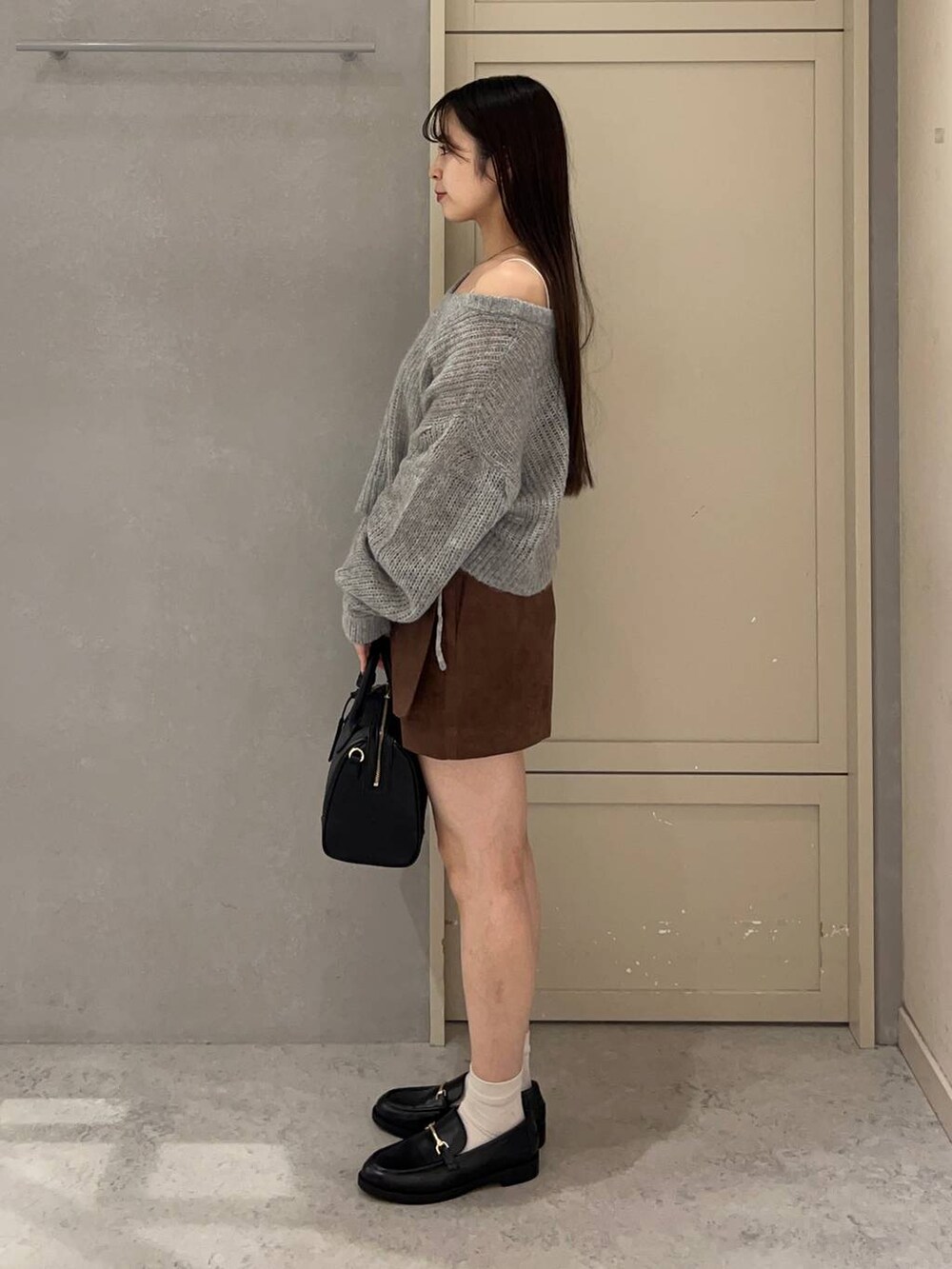 ブラック系のショルダーバッグ、ブラウン系のスカート、ブラック系のローファーを着用したレディースの秋コーディネートの4枚目の写真