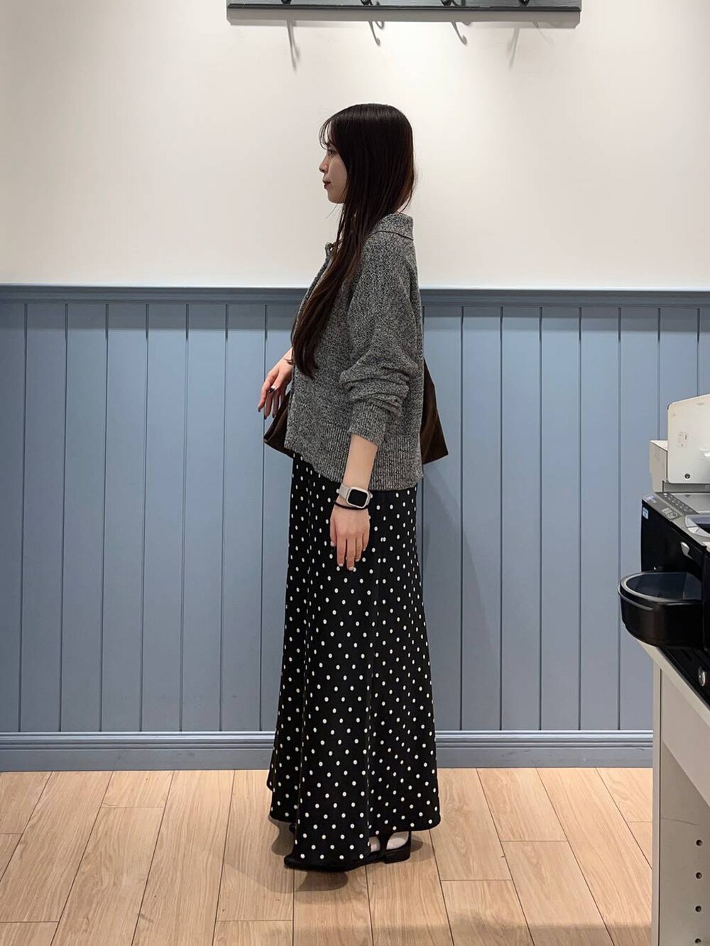 ブラック系のスカート、ブラウン系のショルダーバッグ、グレー系のカーディガン/ボレロを着用したレディースの春コーディネートの2枚目の写真