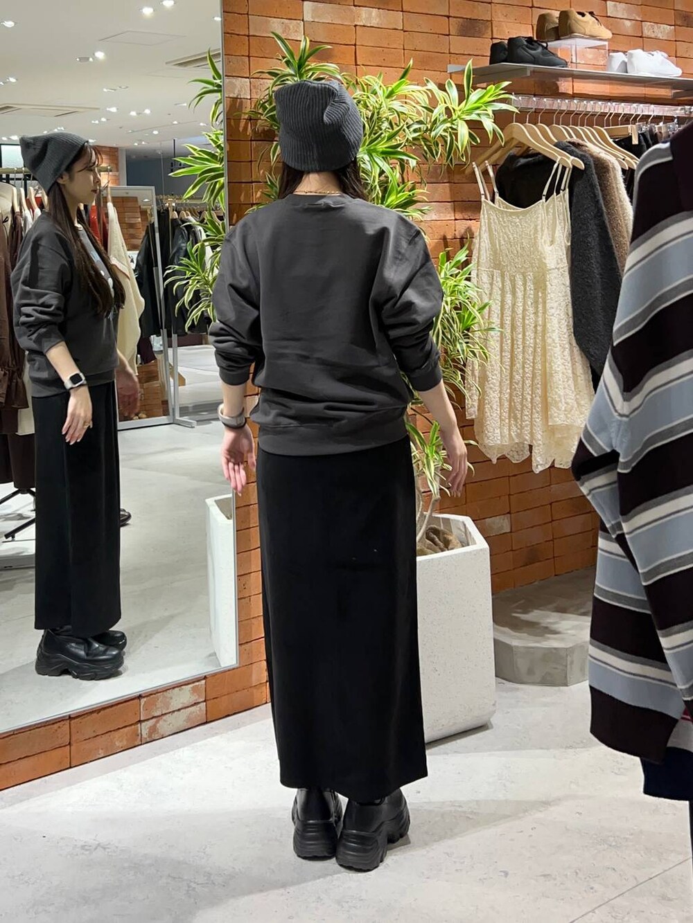 ブラック系のブーツ、ブラック系のスカート、グレー系のスウェットを着用したレディースの秋コーディネートの2枚目の写真