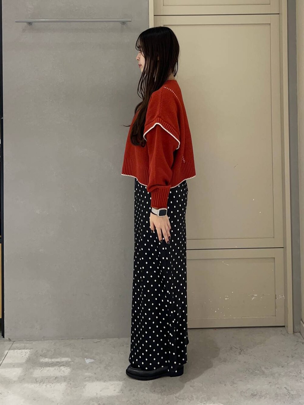 ブラック系のスカート、レッド系のニット/セーター、ブラック系のローファーを着用したレディースの秋コーディネートの3枚目の写真