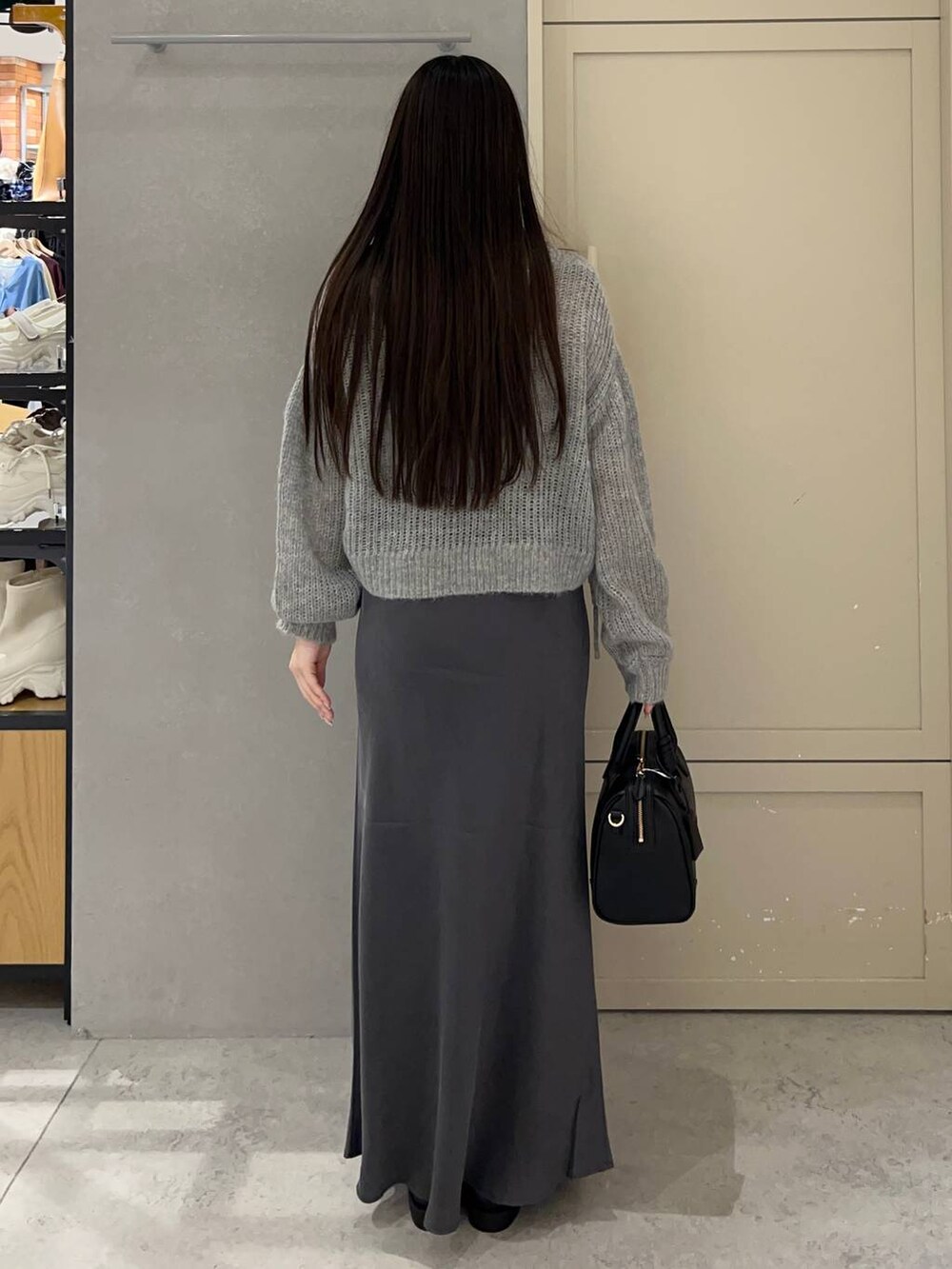 ブラック系のショルダーバッグ、グレー系のスカート、ブラック系のローファーを着用したレディースの秋コーディネートの3枚目の写真