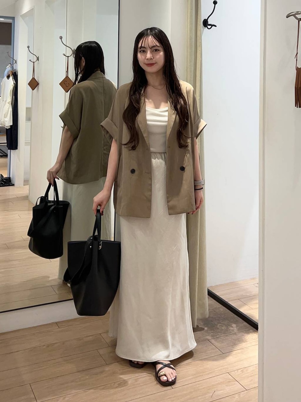ホワイト系のTシャツ/カットソー、ホワイト系のスカート、ブラック系のトートバッグを着用したレディースの夏コーディネートの2枚目の写真