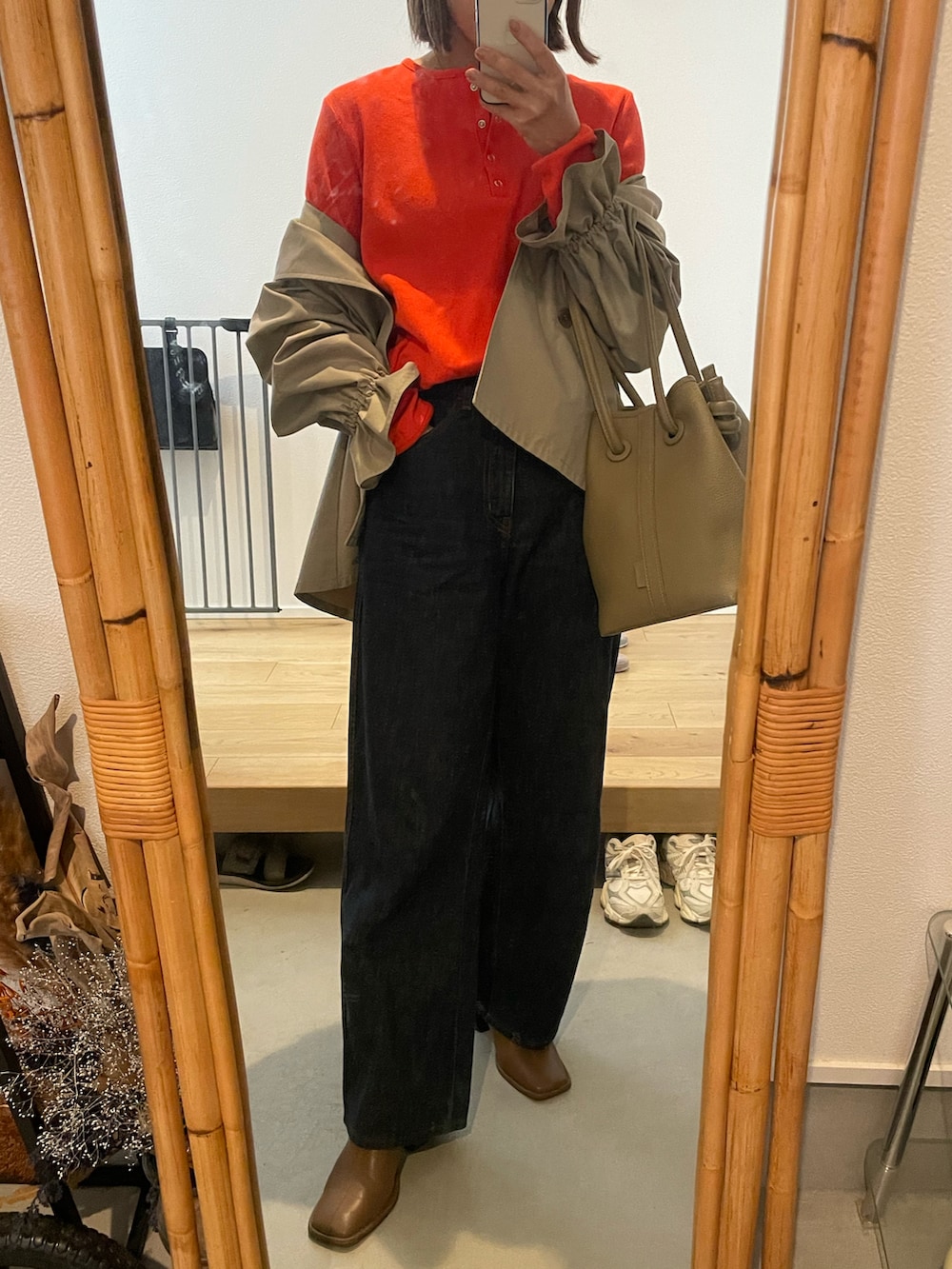 ブルー系のデニムパンツ、ベージュ系のバッグ、ブラウン系のブーツを着用したレディースの春コーディネートの2枚目の写真