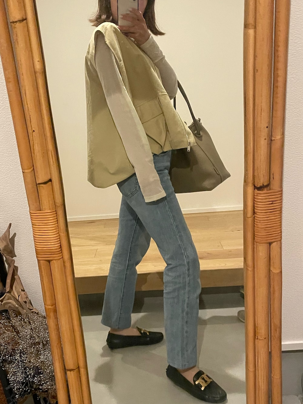 ブルー系のデニムパンツ、ブラック系のシューズ、イエロー系のベストを着用したレディースの春コーディネートの3枚目の写真