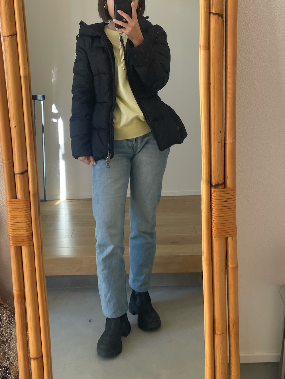 ブルー系のデニムパンツ、ブラック系のブーツ、ブラック系のダウンジャケット/コートを着用したレディースの冬コーディネートの2枚目の写真